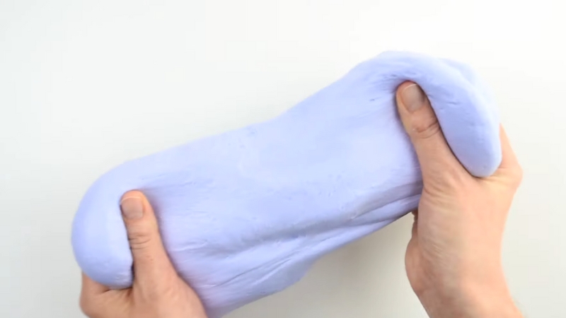 Hands Stretching a Piece of Soft, Light Purple Homemade Slime