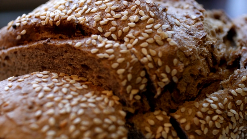 A close-up of a loaf of whole wheat bread topped with sesame seeds